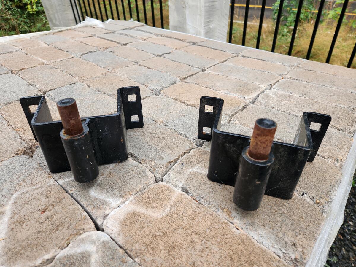 L-shaped steel post anchors bolted to the concrete piers, ready for the Douglas fir corner posts